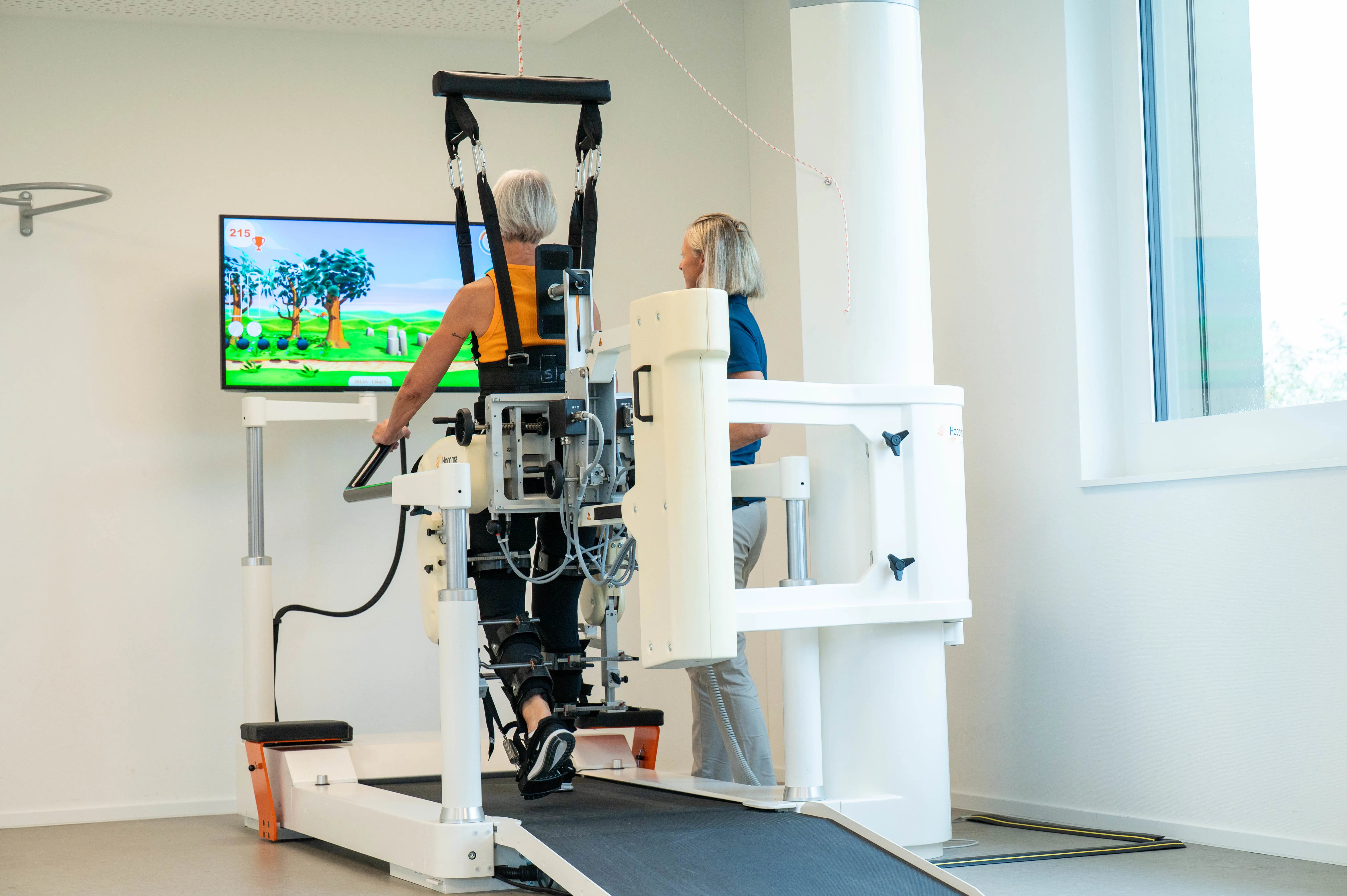 Patientin während Gangtherapie auf Lokomat begleitet von einer Therapeutin.