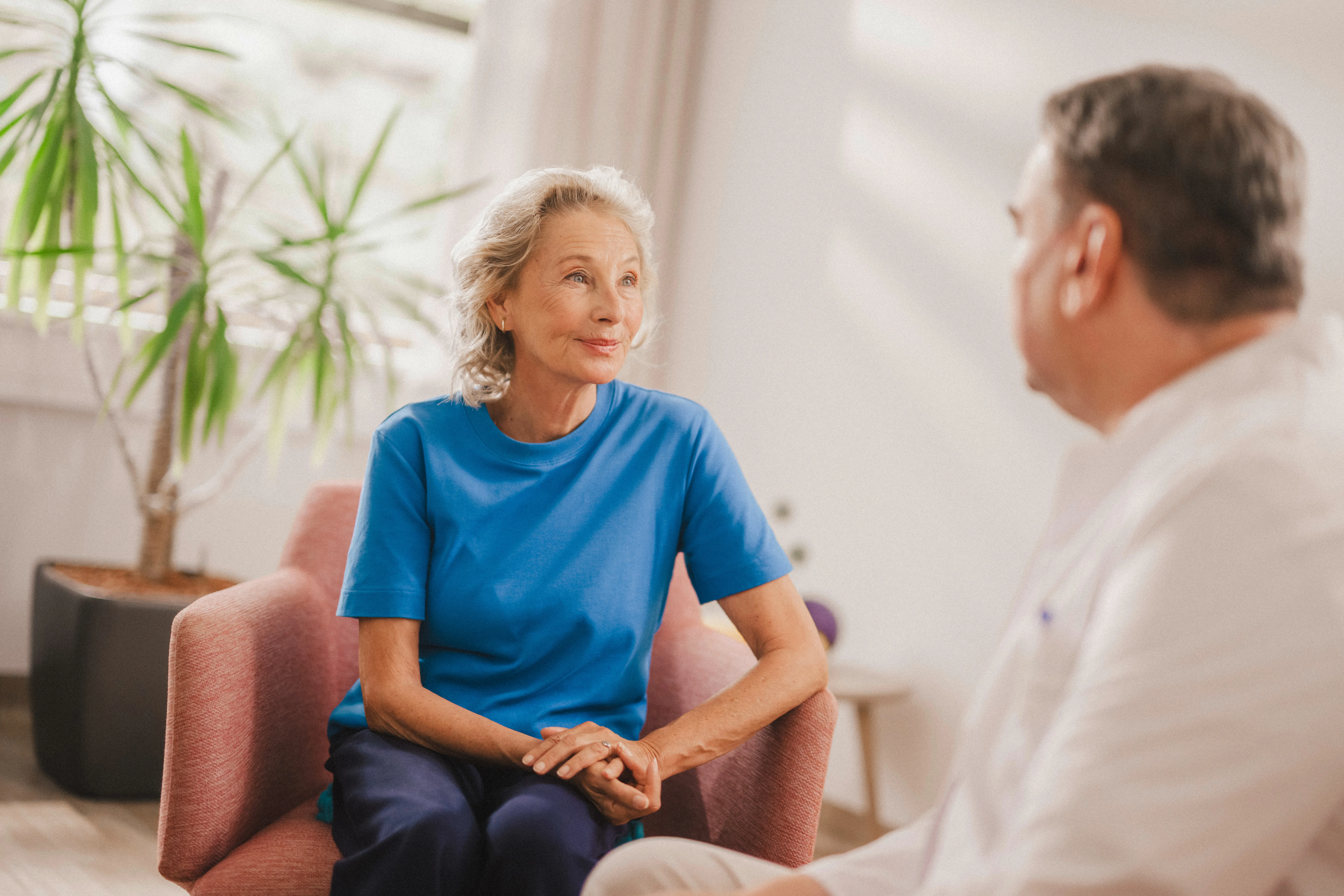 Eine Patientin und ein Arzt im Gespräch, sitzend auf Sesseln.