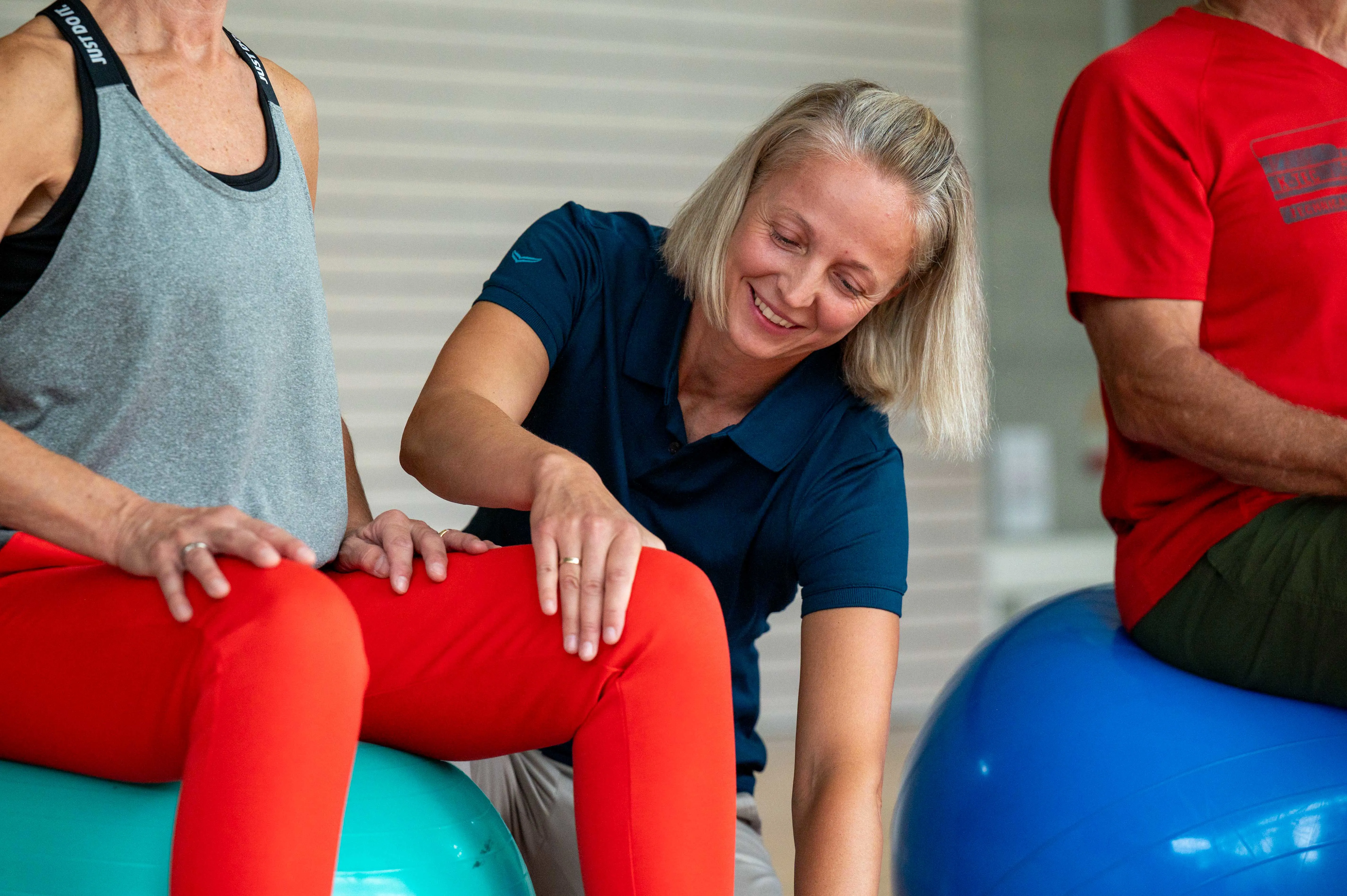 Therapeutin richtet die Patientin korrekt für eine Übung auf dem Gymnastikball.