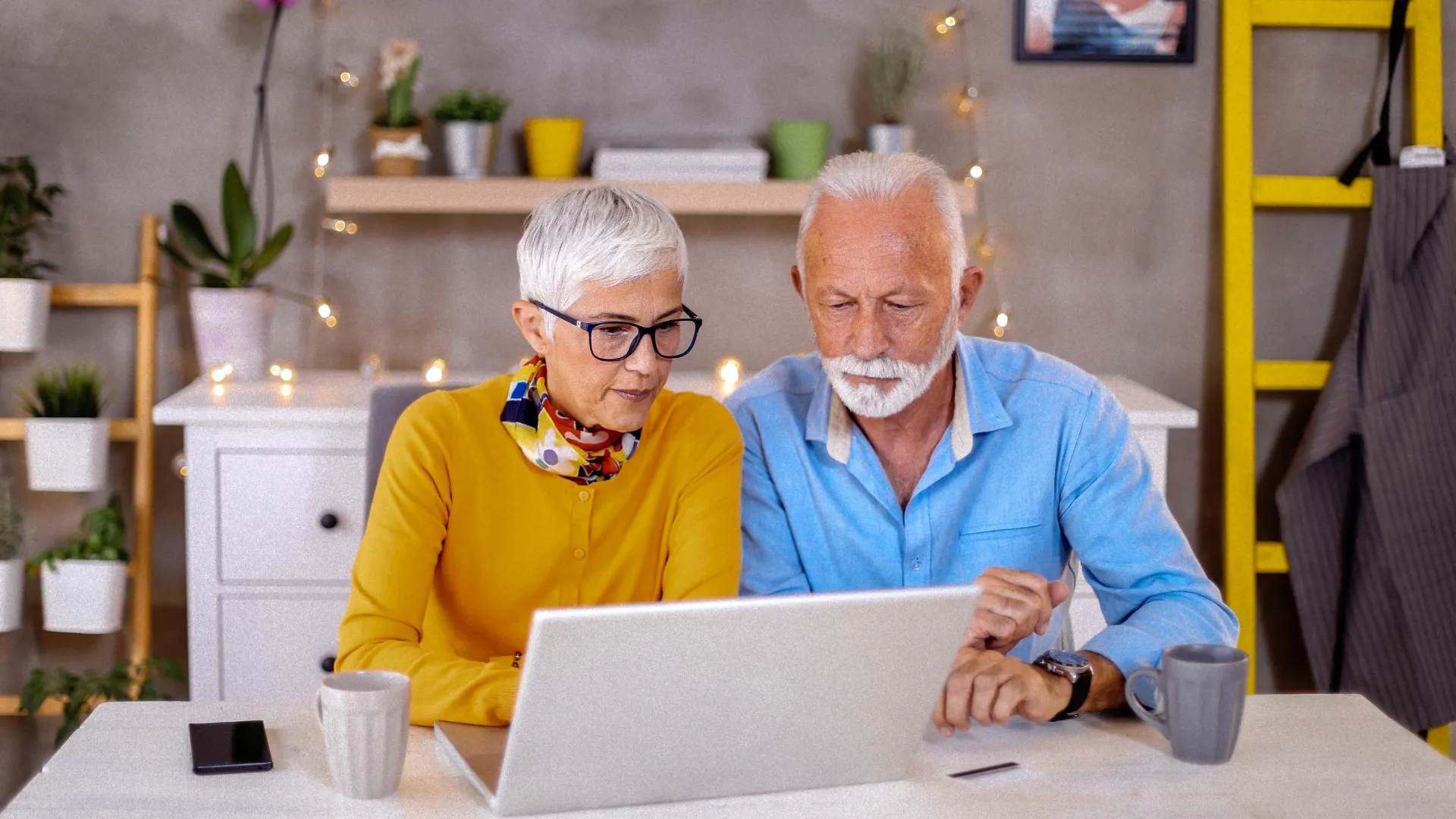 Mann und Frau sitzen am Tisch an einem aufgeklappten Laptop.