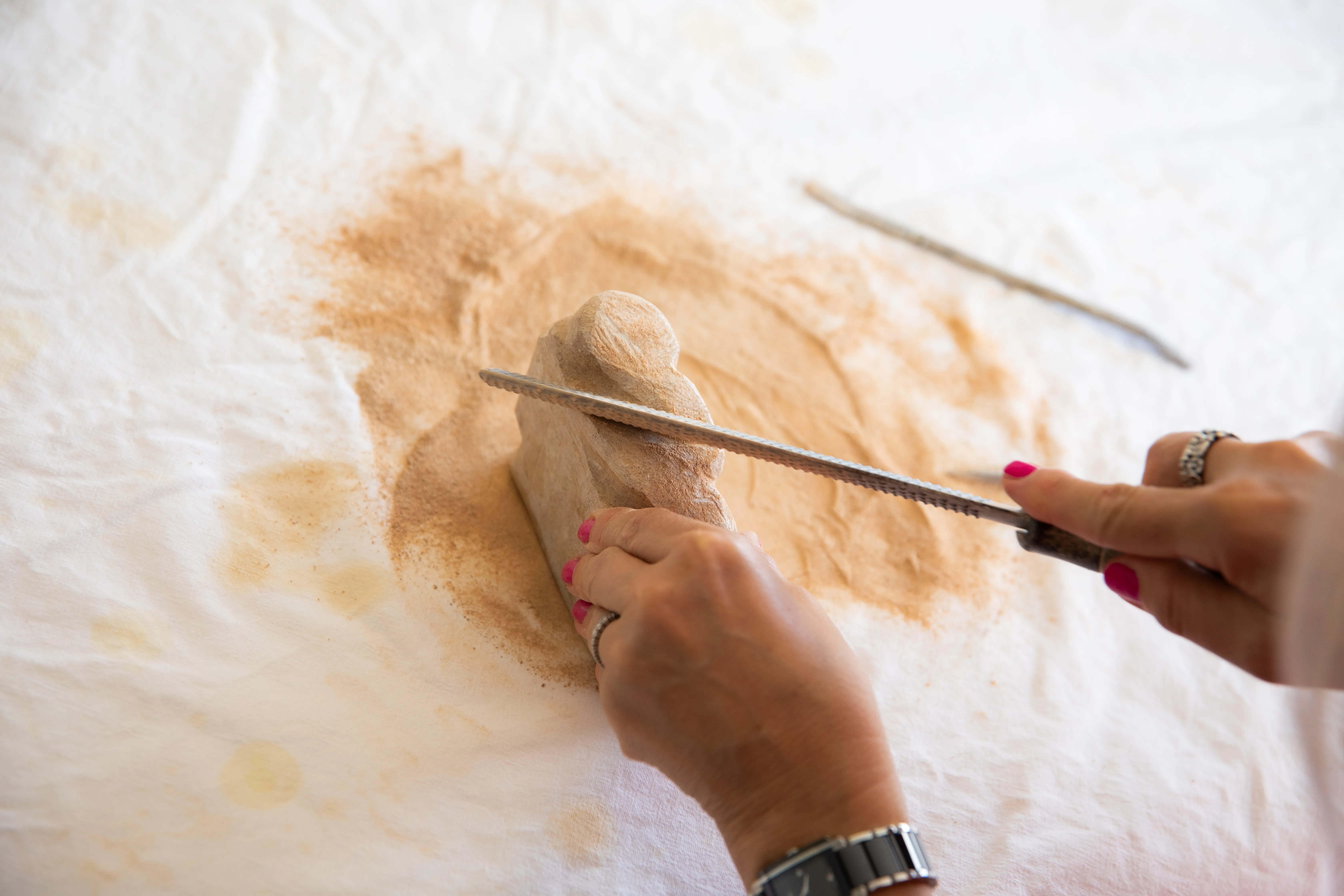 Frauenhände beim Schleifen von Holz im Rahmen der Ergotherapie.
