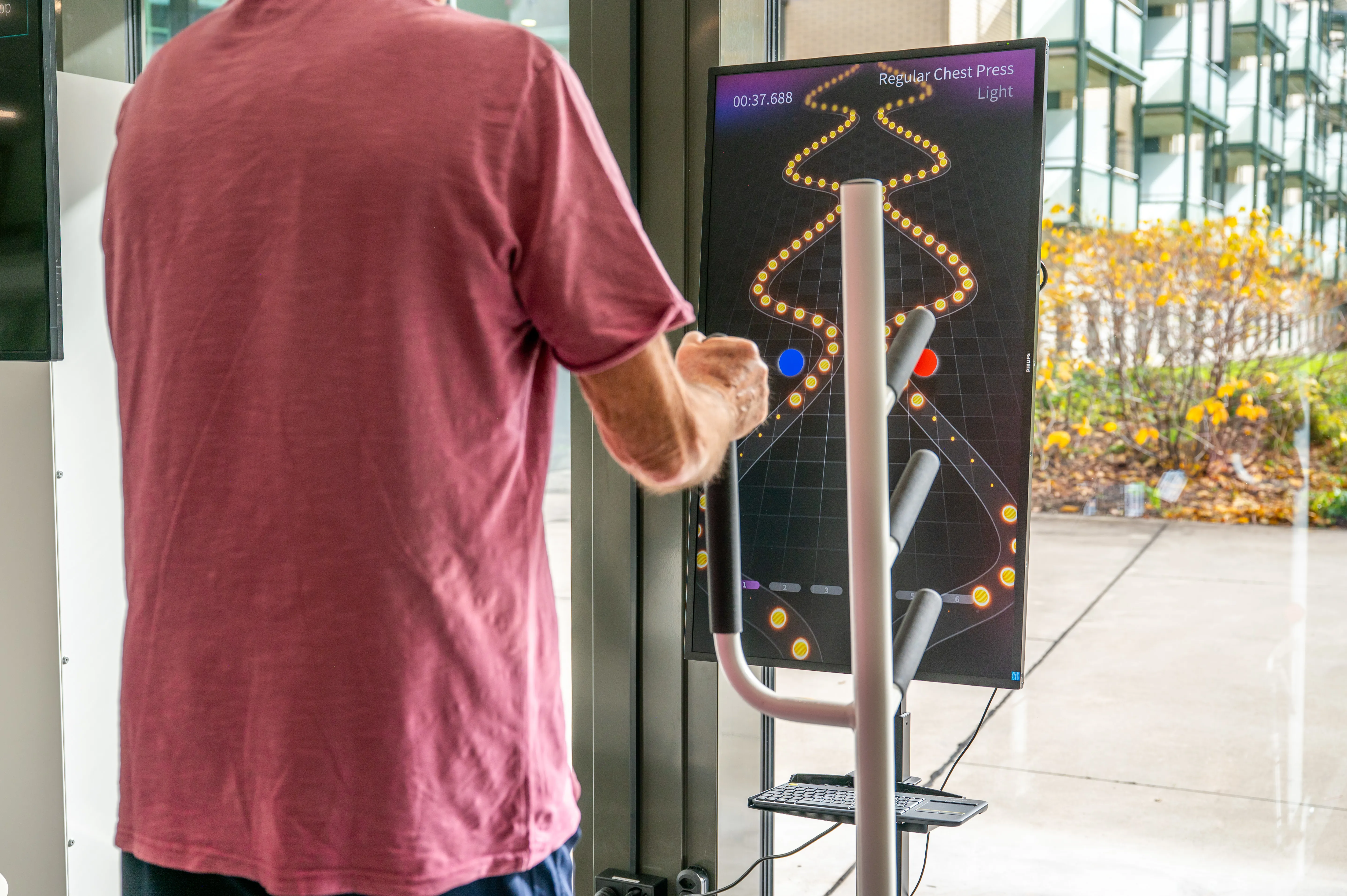 Patient von hinten bei der Therapie der oberen Extremitäten an einem Robotikgerät.