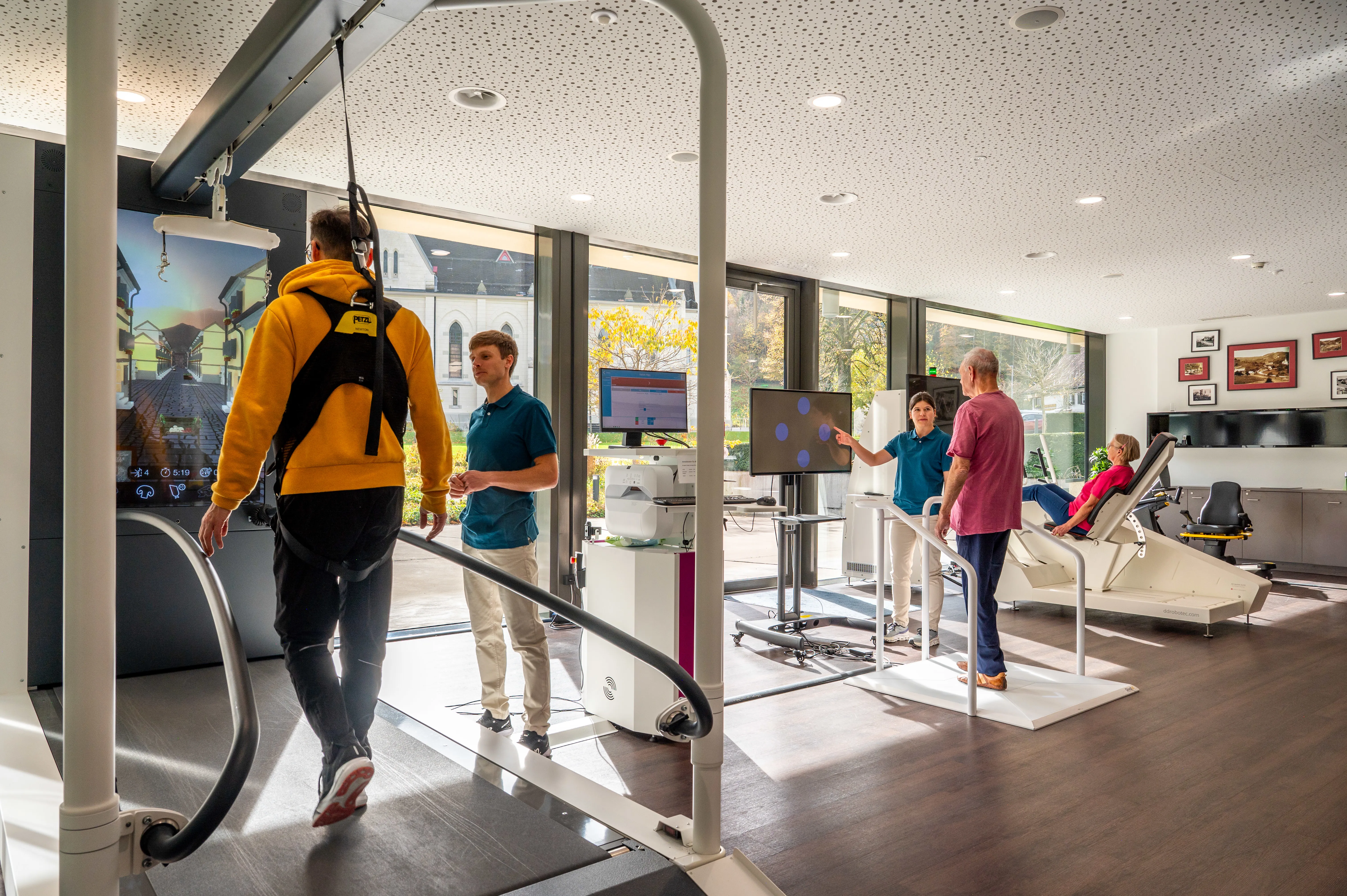 Ansicht des Robotikzentrums in der Rehaklinik Dussnang mit Patient:innen auf Robotikgeräten begleitet von Therapeut:innen.