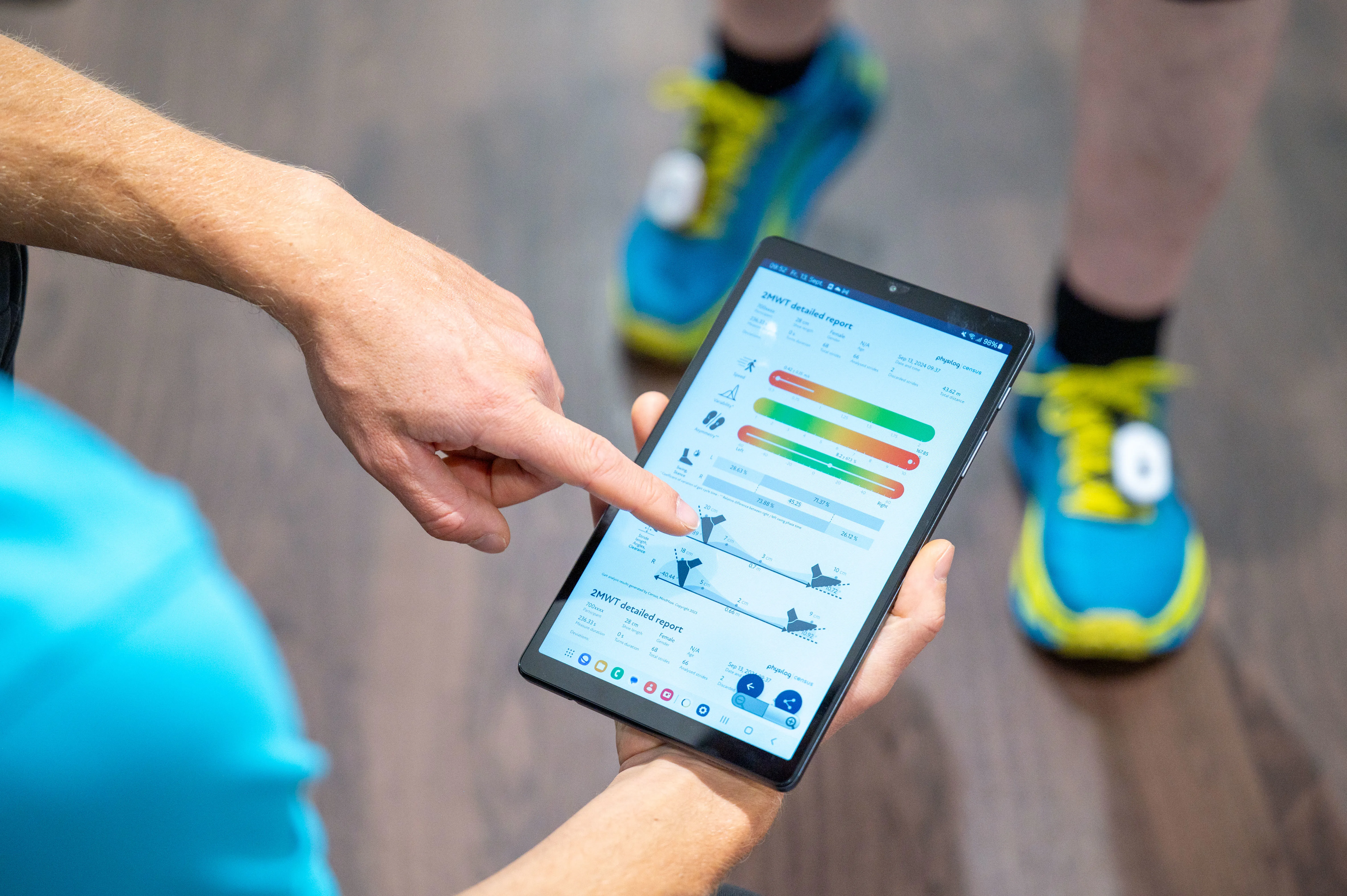 Ein Therapeut schaut sich auf dem Tablet die Fortschritte eines Gangtrainings an.
