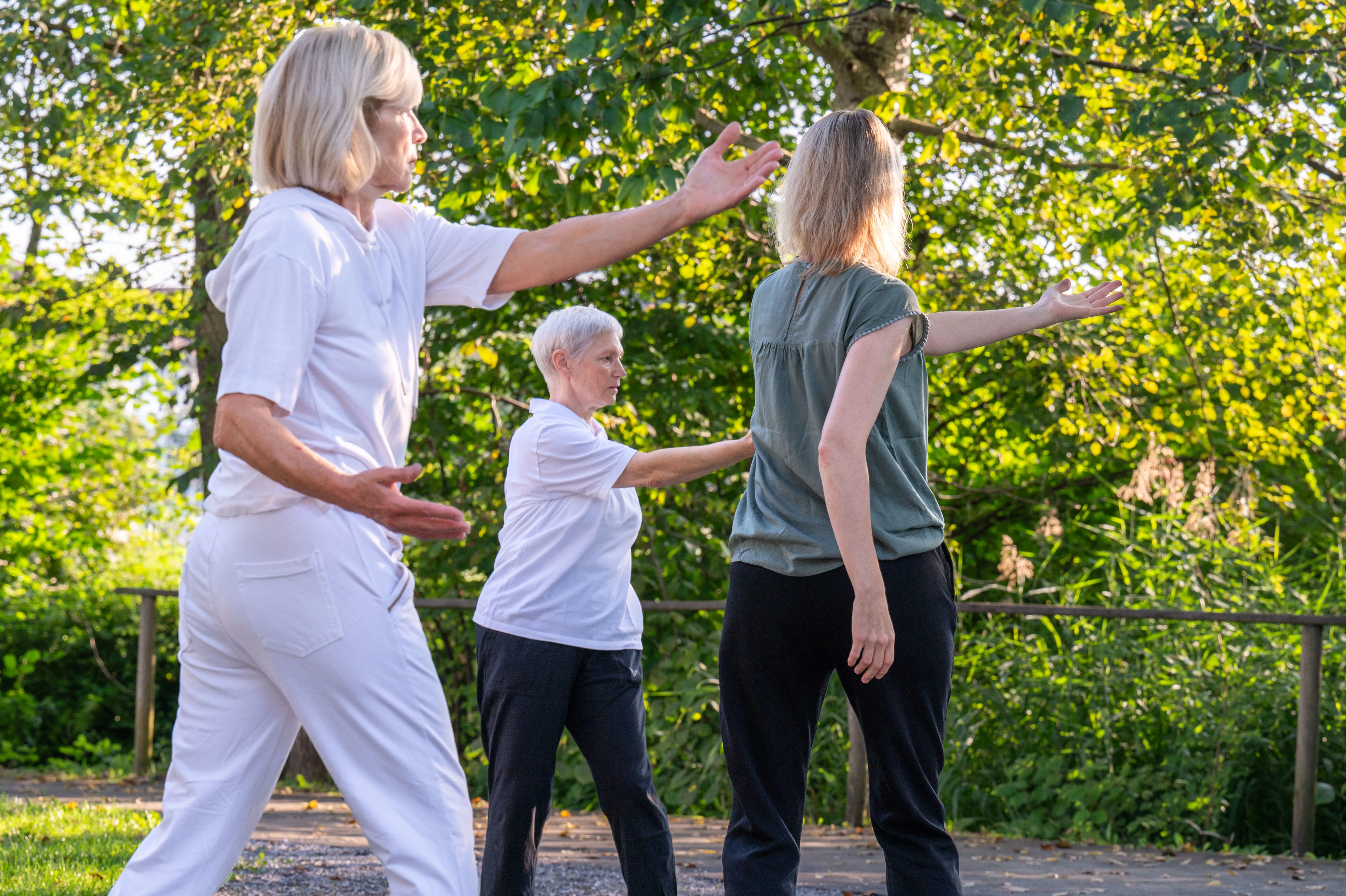 Zwei Patientinnen und eine Therapeutin während einer Qi-Gong Stunde im Klinikpark.