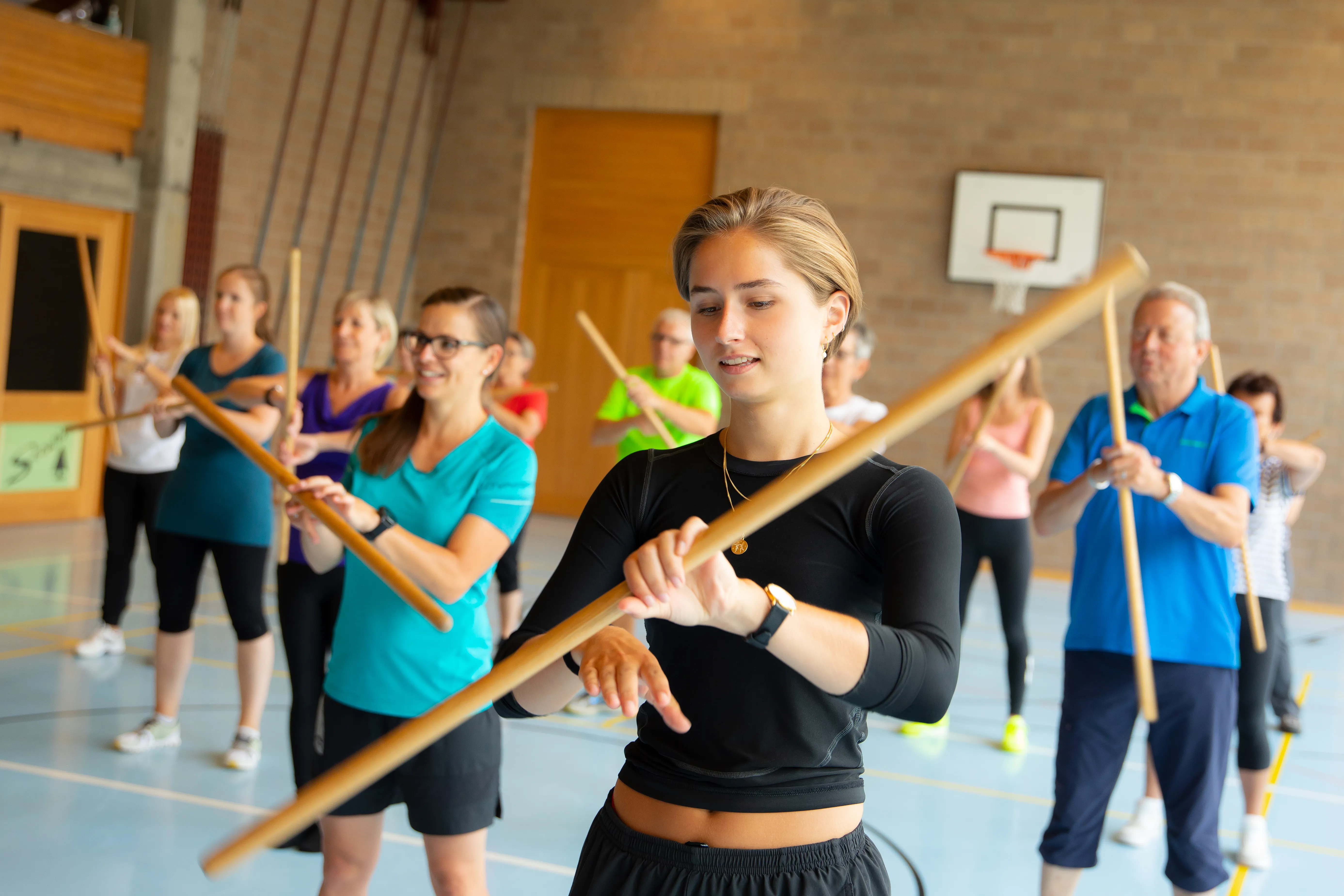 Physiotherapiestunde mit Patient:innen während einer Übung mit einem Holzstab.