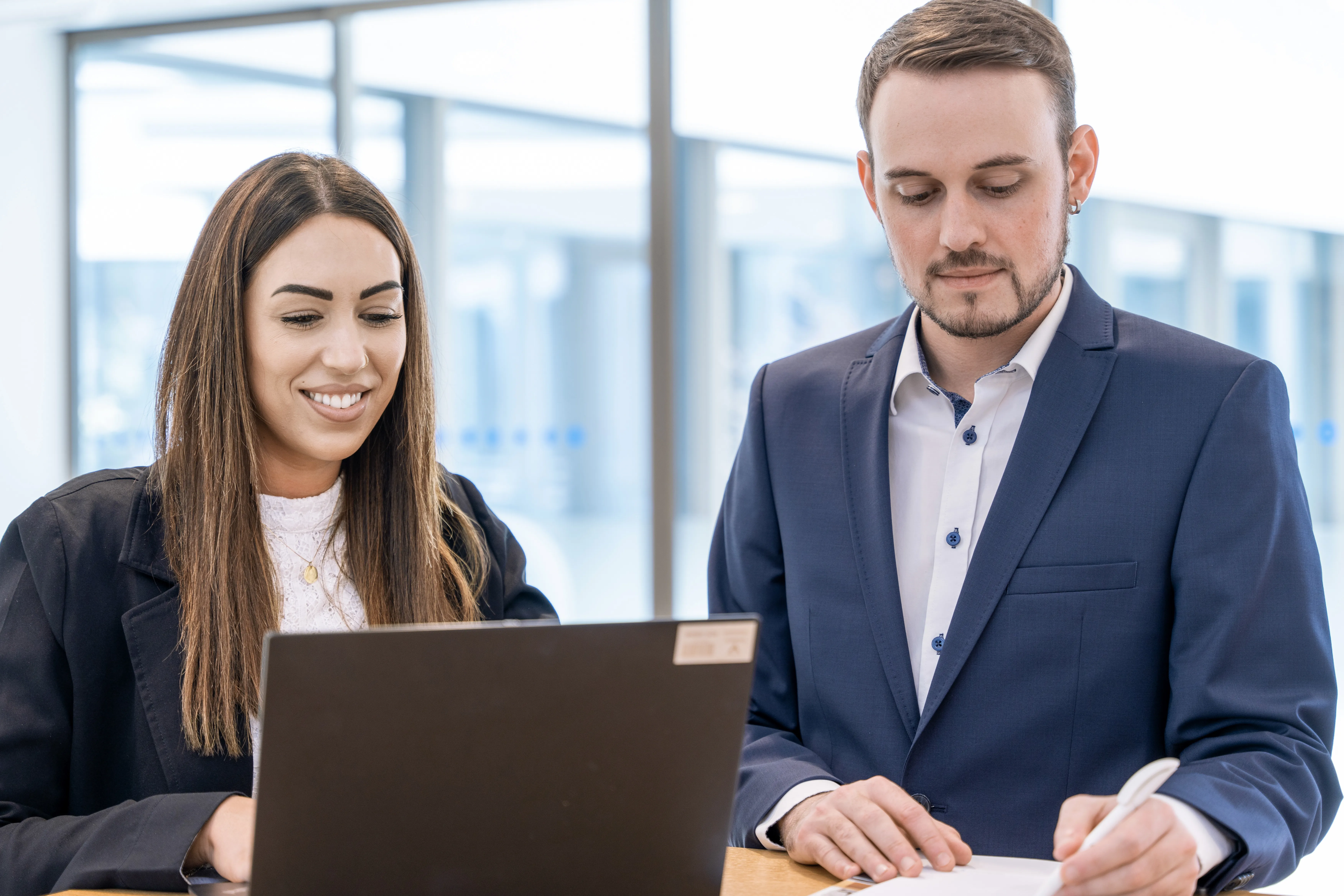 Mitarbeiter des International Office von VITREA Schweiz arbeiten stehend am Laptop.