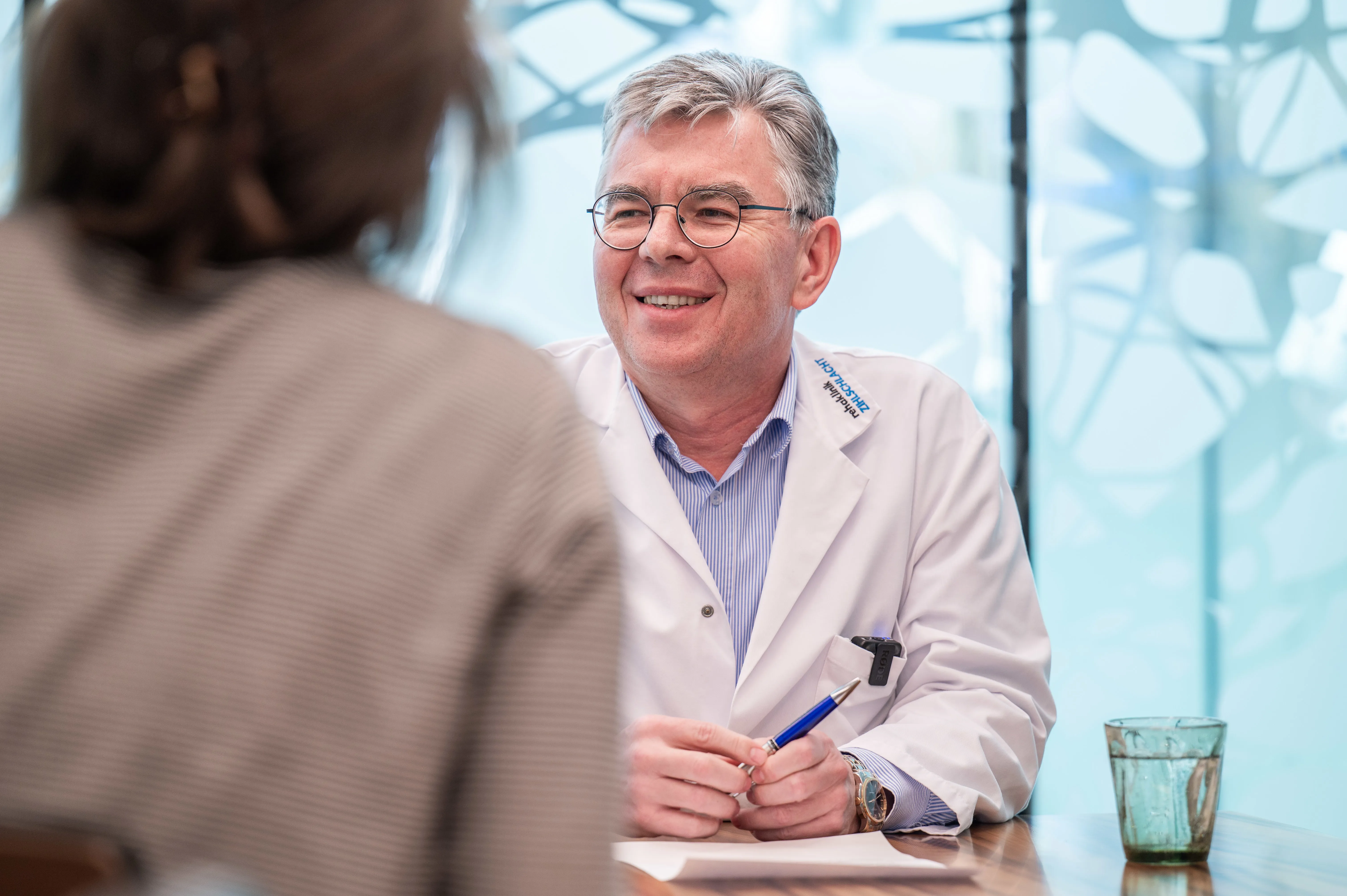 Dr. Stefan Schuko im Gespräch mit Person, die nur von hinten sichtbar ist.