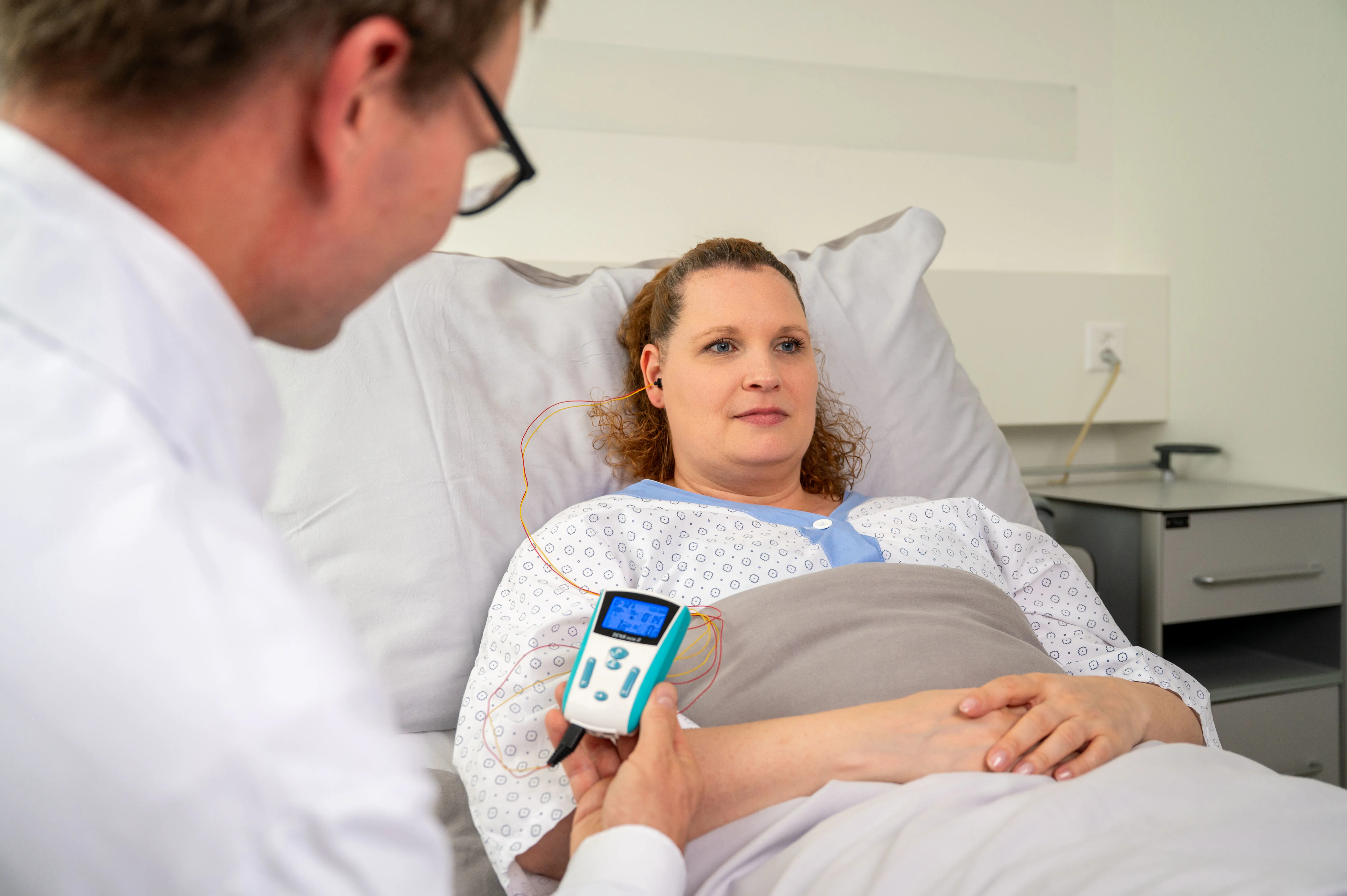 Ein Arzt führ die Vagusnervstimulation bei einer Patientin durch, die im Bett liegt.